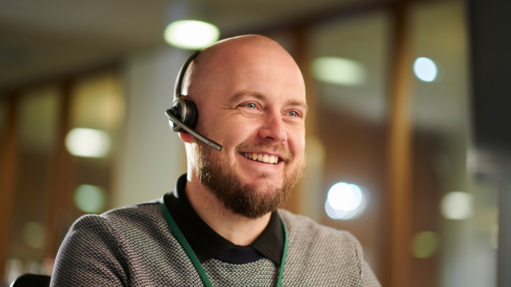 Glad man med headset, redo svara i telefon