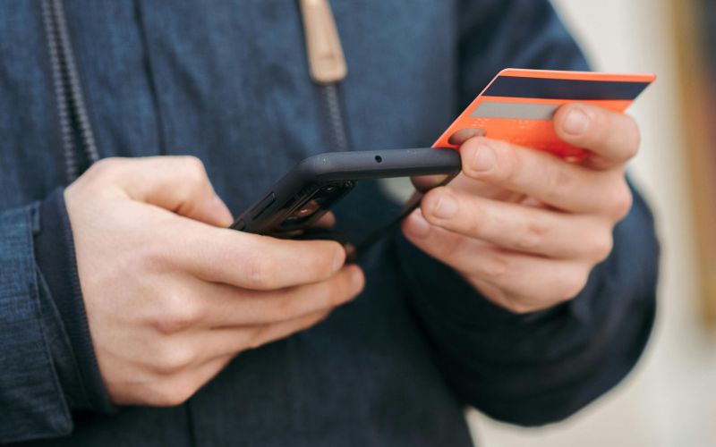 en man håller kontokort och telefon