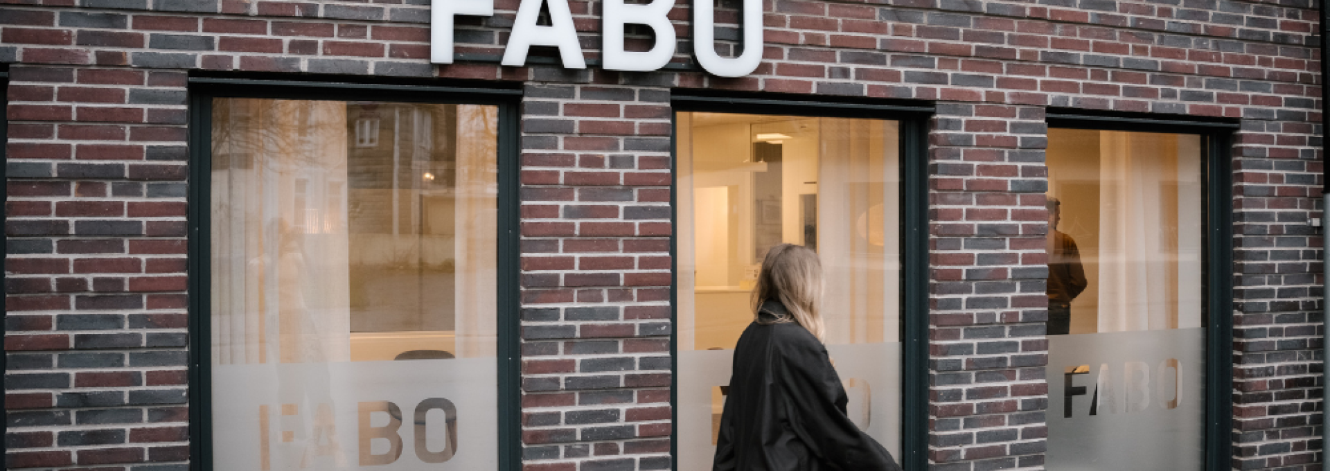 Fabos husfasad, kvinna går framför huset på trottoaren