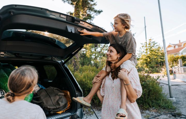 En familj packar in saker i bagaget på en bil