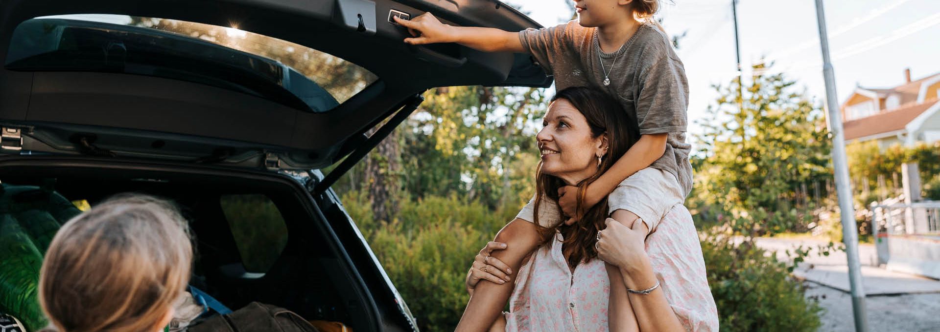 En familj packar in saker i bagaget på en bil