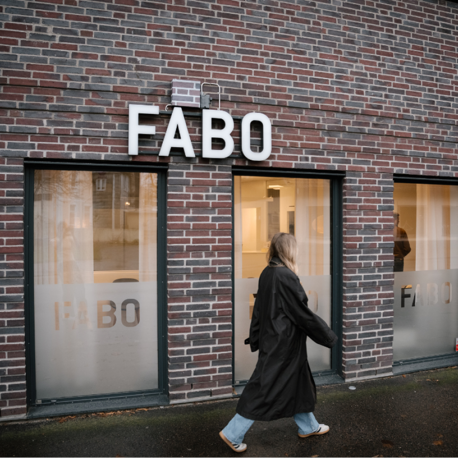 Fabos husfasad, kvinna går framför huset på trottoaren