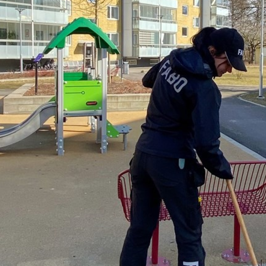 Ung kvinna som krattar löv i ett bostadsområde