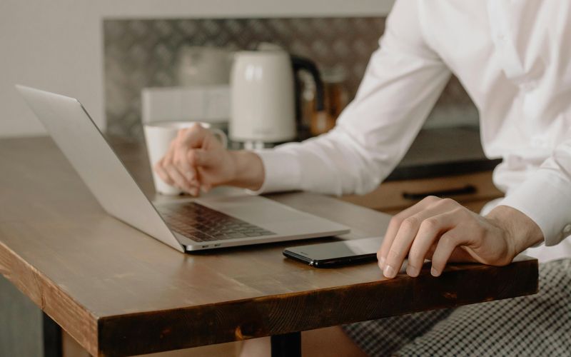 en kvinna sitter med laptop och telefon