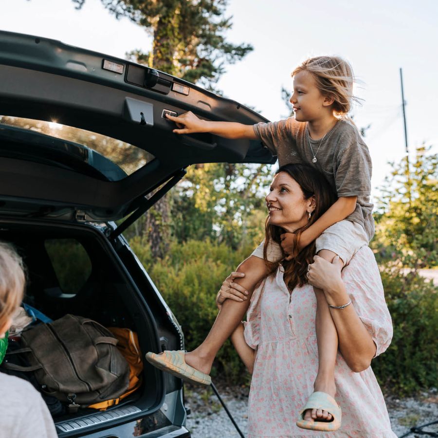 En familj packar in saker i bagaget på en bil