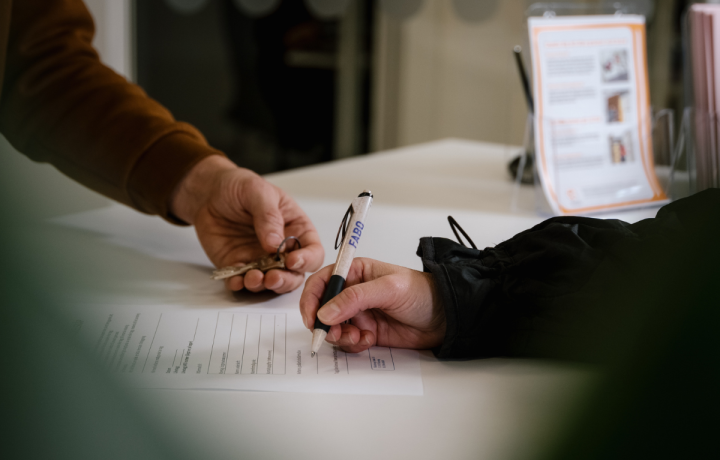 Två personer, vars händer bara syns över ett papper - den ena skriver under ett kontrakt